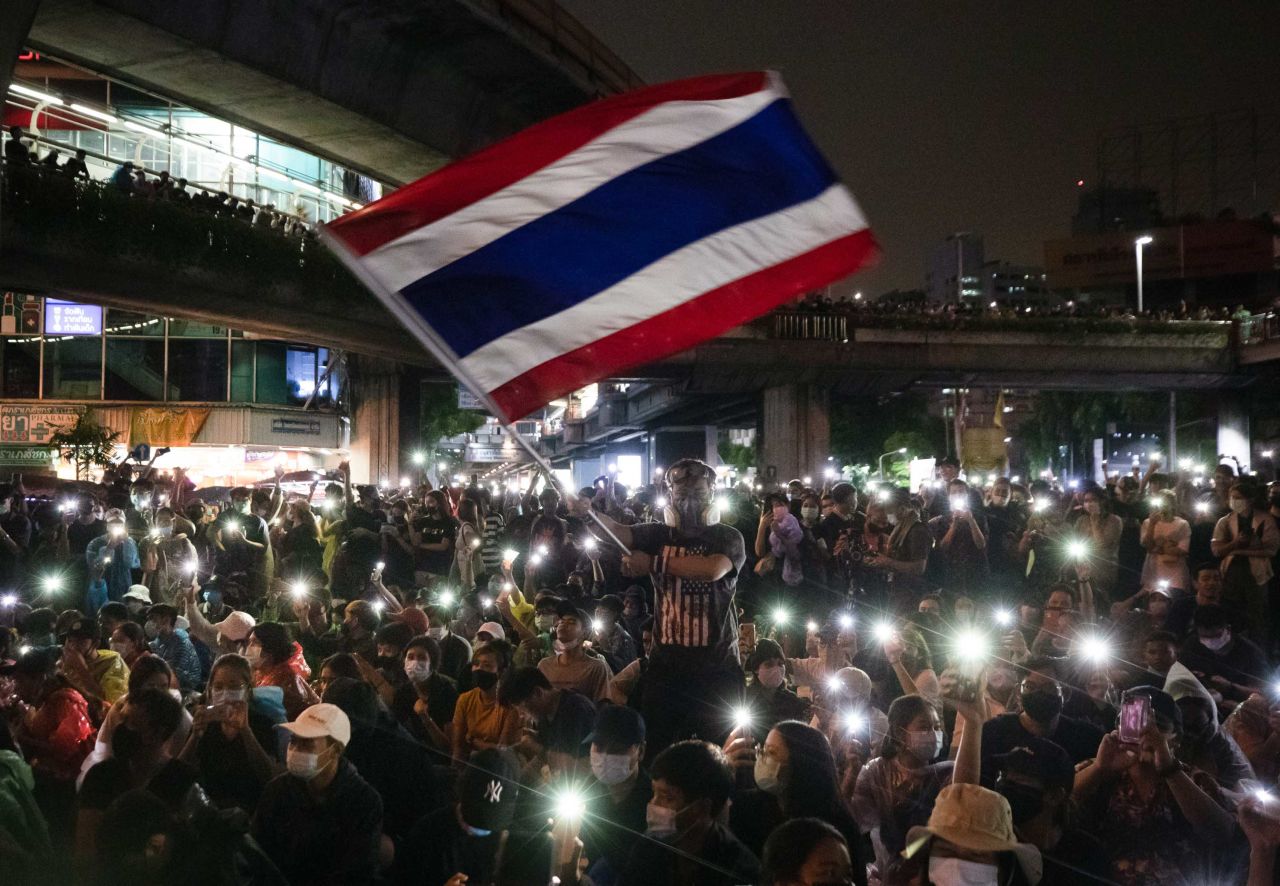 A protester waves Thailand's national flag as others shine their mobile phone lights on October 18.