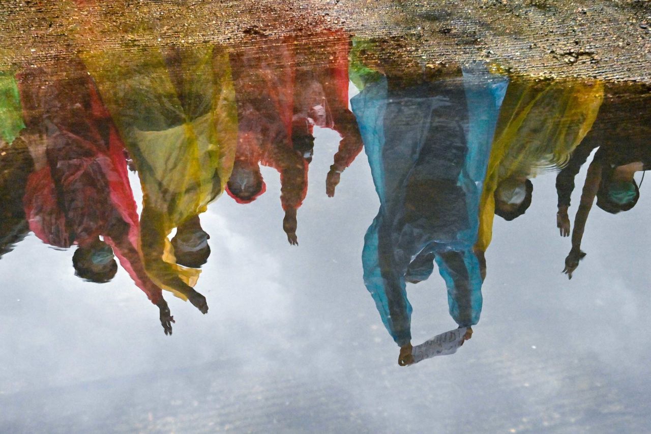 Demonstrators wearing ponchos are reflected in a puddle at Wongwian Yai in Bangkok on October 17, as they defy an emergency decree banning gatherings.