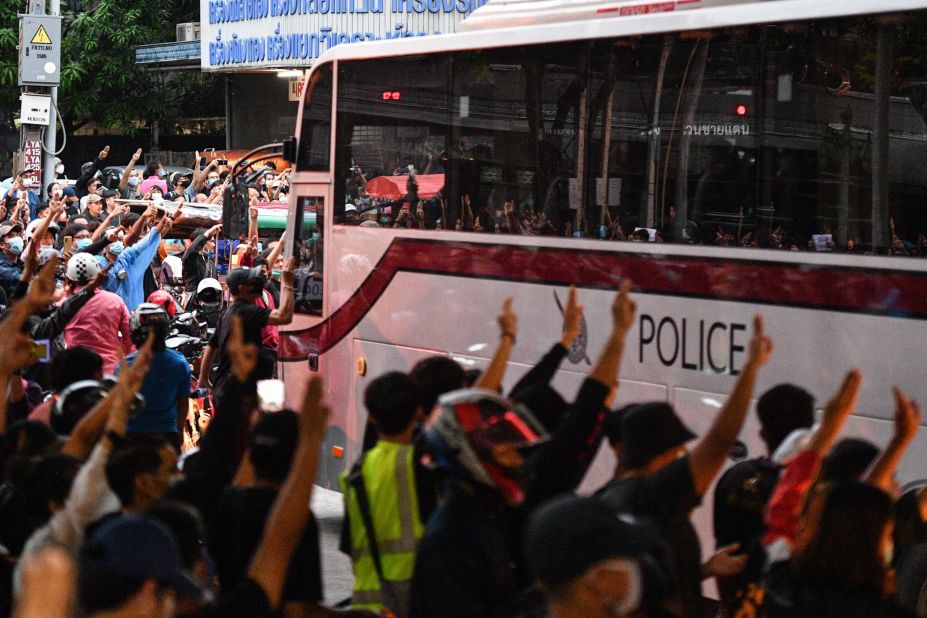 Pro-democracy protesters give the three-finger salute as a police bus passes at Wongwian Yai on October 17.