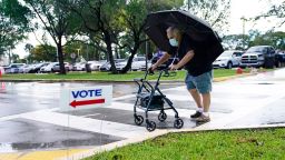 Franklin Castellon, 76, shields himself from the rain as he walks to an early voting site, Monday, Oct.19, 2020, in Miami. 