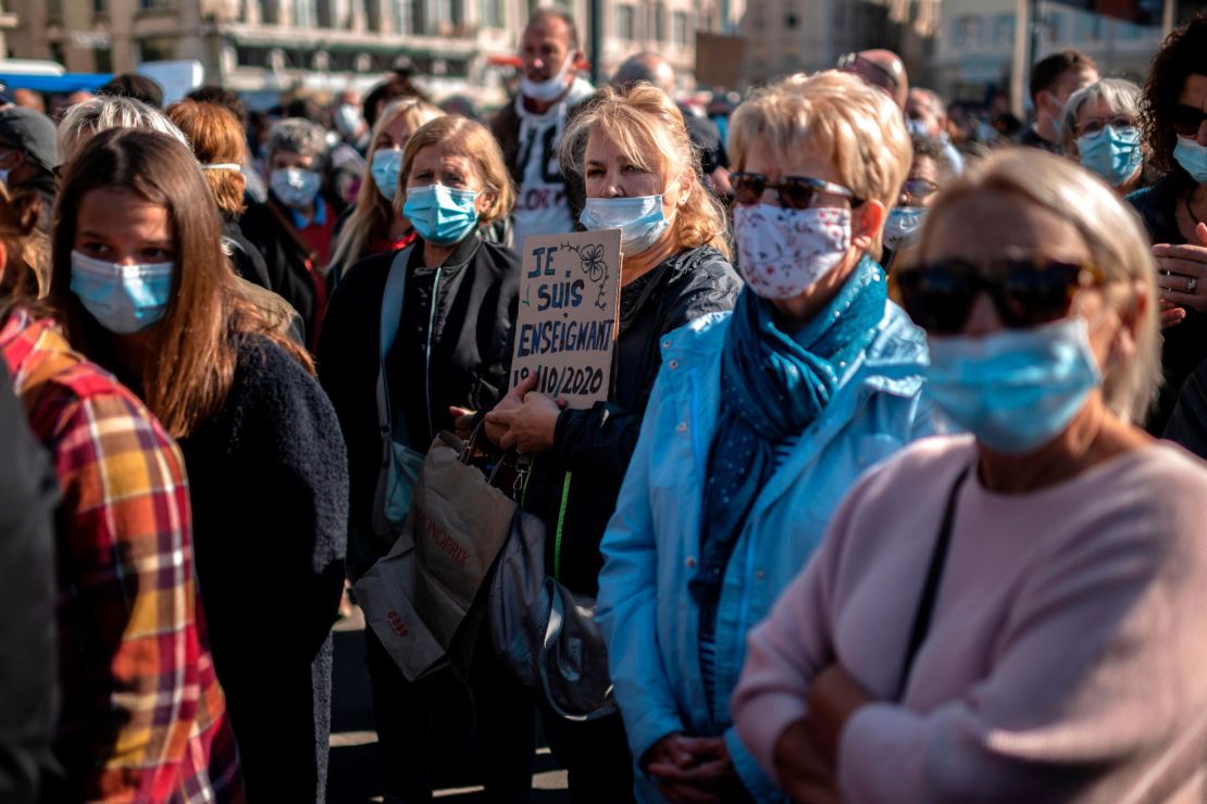 A woman holds a placard reading "I am a teacher" as people gather on the Vieux Port in Marseille on October 18, in homage to history teacher Samuel Paty.