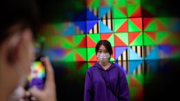 This picture taken on October 18, 2020 shows a young woman posing for a photo taken by a friend (L) in front of an art installation in the 798 art district in Beijing. (Photo by NICOLAS ASFOURI / AFP) (Photo by NICOLAS ASFOURI/AFP via Getty Images)