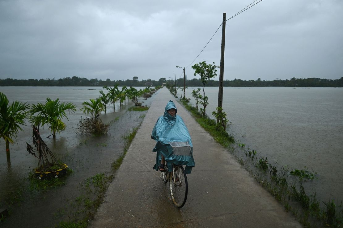 A man rides his bicycle past flood waters during heavy rain showers in Hai Lang district in central Vietnam's Quang Tri province on October 16, 2020.