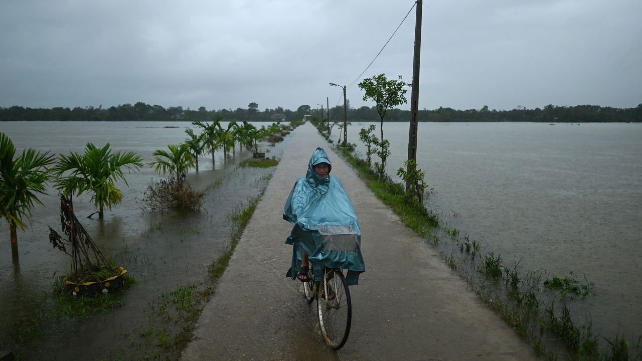A man rides his bicycle past flood waters during heavy rain showers in Hai Lang district in central Vietnam's Quang Tri province on October 16, 2020.