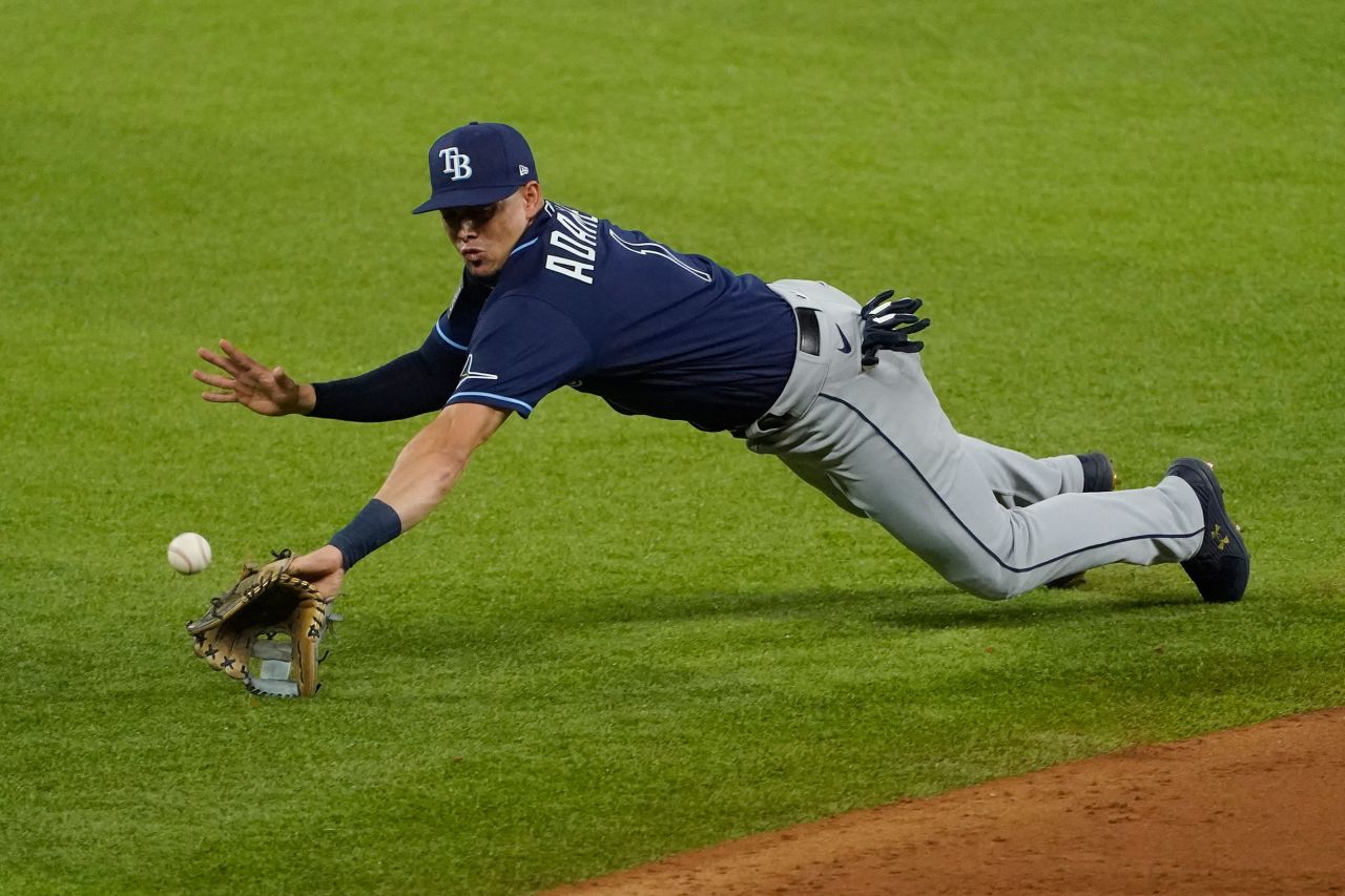 A ground ball hops over the outstretched glove of Rays shortstop Willy Adames.