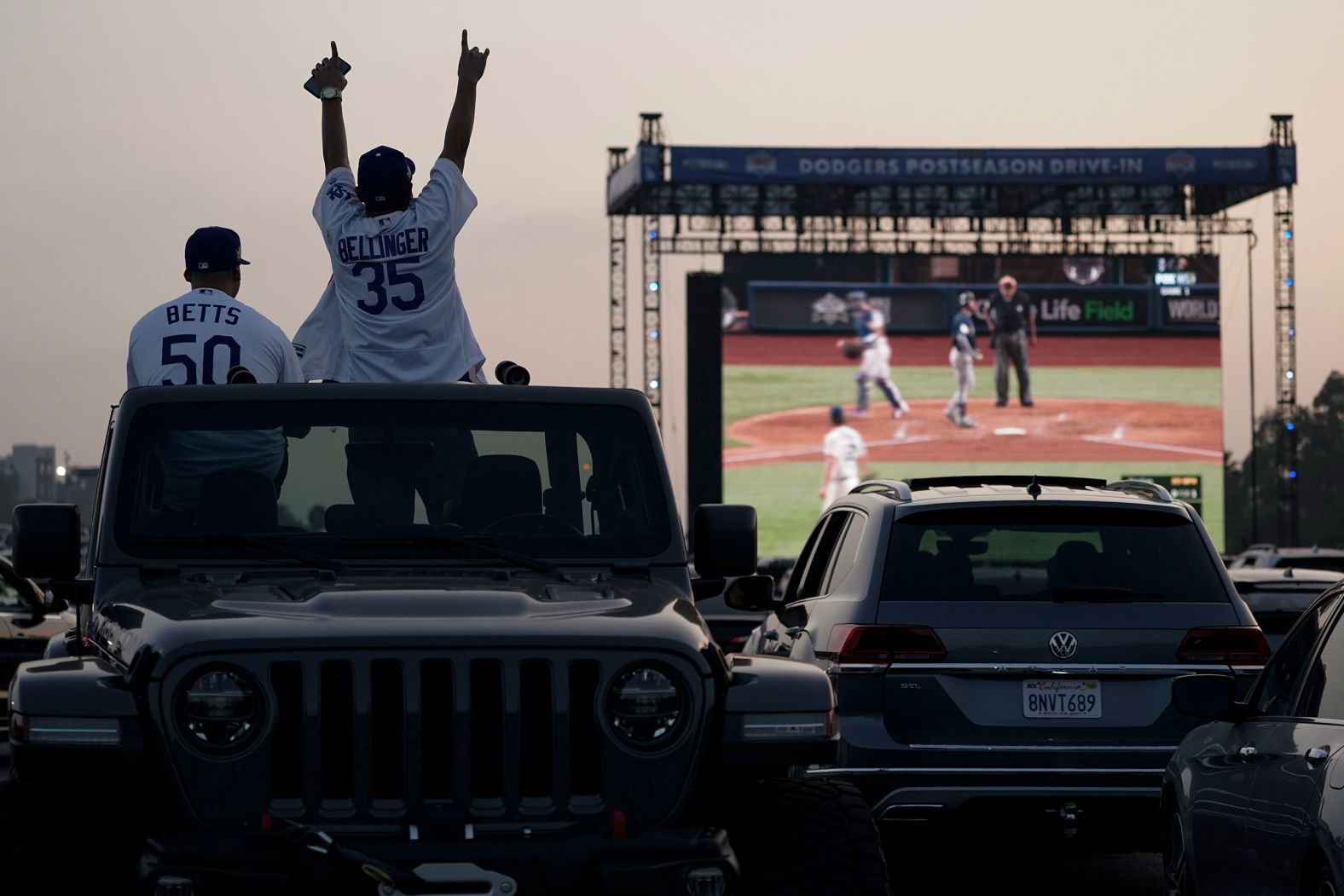 Mike Kim and Jacob Zelaya cheer from their car while watching the game outside Dodger Stadium in Los Angeles. Due to the coronavirus pandemic, Major League Baseball decided to play all World Series games at a neutral site in Arlington, Texas.