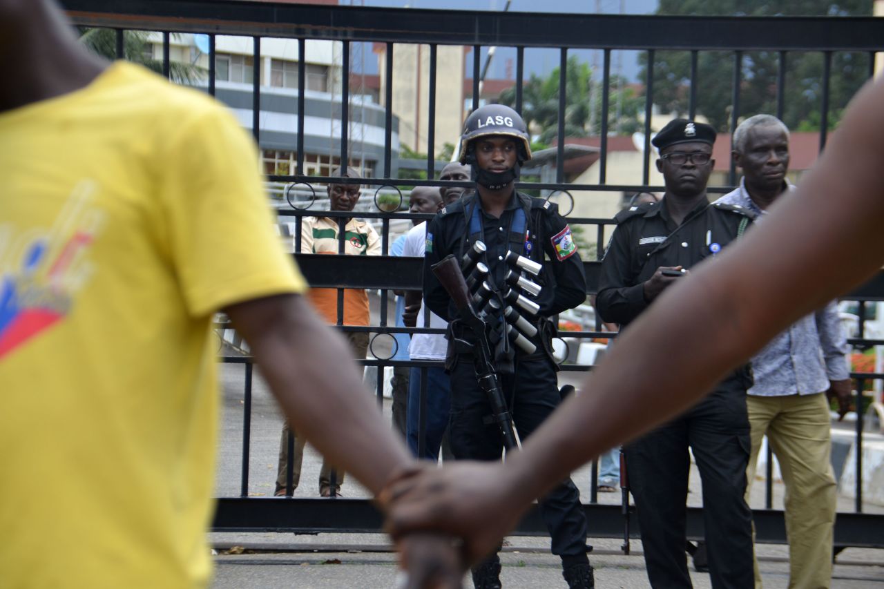 Protesters hold hands in front of police officers during a peaceful demonstration at the Alausa Secretariat.