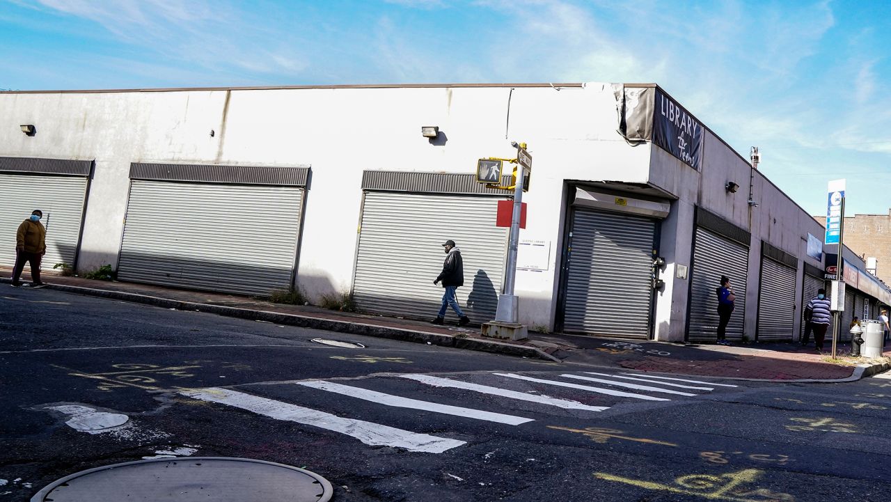 Pedestrians pass shuttered storefronts on Thursday, Oct. 15, 2020, as restrictions are imposed due to a COVID-19 infection rate increase in the Far Rockaway neighborhood of the borough of Queens in New York. After shutdowns swept entire nations during the first surge of the coronavirus earlier this year, some countries and U.S. states are trying more targeted measures as cases rise again around the world. (AP Photo/John Minchillo)