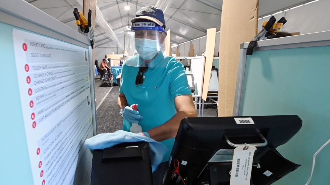 A voting booth is sanitized between voters inside a tent at a shopping center on the first day of in-person early voting in Las Vegas, Nevada.