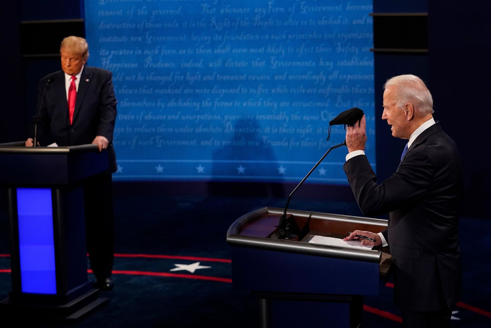 Biden holds up a mask as Trump takes notes during the debate section about the coronavirus.