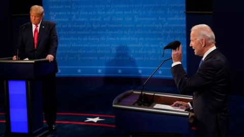 Biden holds up a mask as Trump takes notes during the debate section about the coronavirus.