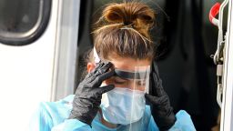 After changing PPE, an LPN dons her face shield at an Aveanna Healthcare and Fallon Ambulance walk-up COVID-19 testing site during the continuing coronavirus pandemic in Lynn, MA on Oct. 19, 2020. (Photo by Pat Greenhouse/The Boston Globe via Getty Images)