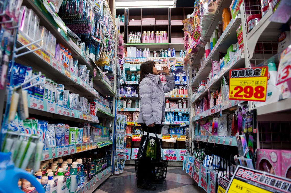 A woman browses products on a shelf in a discount store in the area of Shibuya in Tokyo, Japan, on March 1, 2013. 