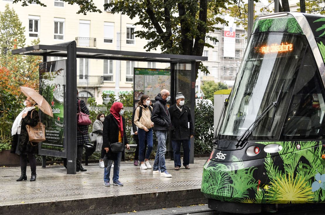People wearing protective face masks  wait for a tram on October 22, 2020 in a street of Saint-Etienne, central eastern France. 