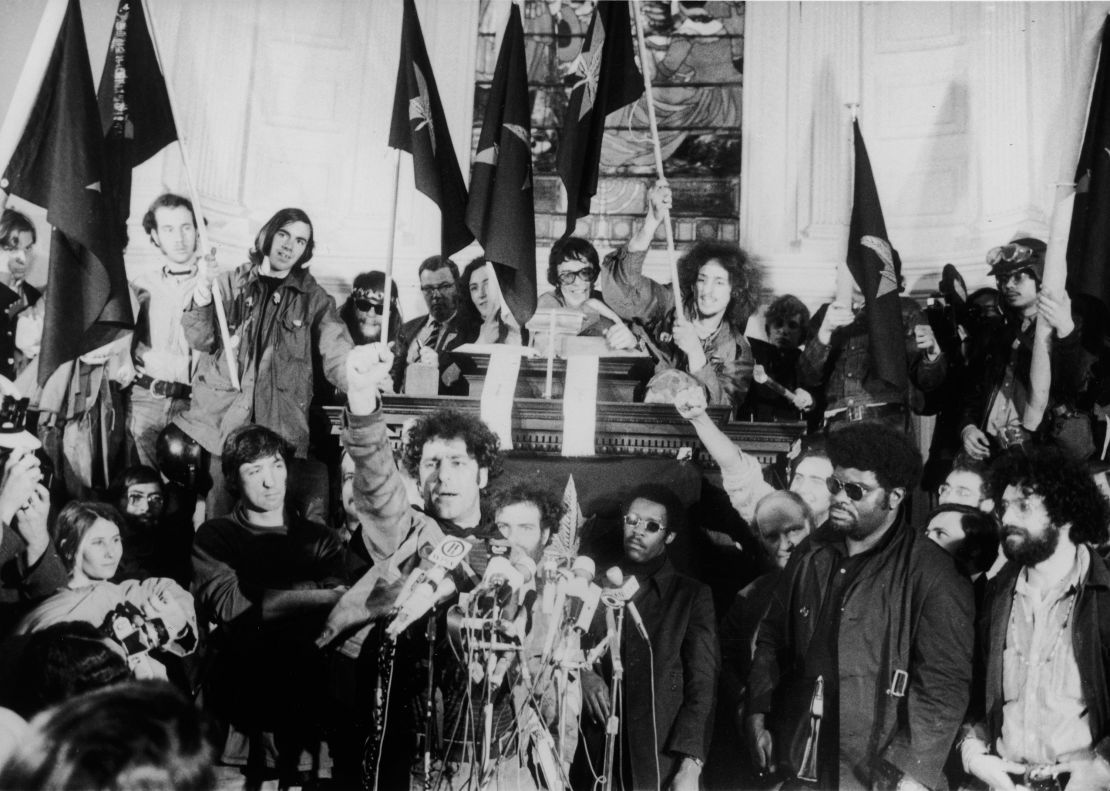 American political activist Abbott "Abbie" Hoffman raises a fist from behind a bank of microphones during an unidentified rally in New York, late 1960s.