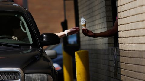 A driver receives a soft serve ice cream cone from an employee working the drive-thru at a McDonald's Corp. restaurant in Louisville, Kentucky.