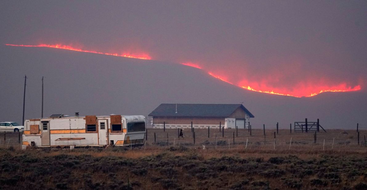 Flames rise from mountain ridges near a farmstead as a wildfire burns near Granby, Colorado, on Thursday, October 22, 2020.