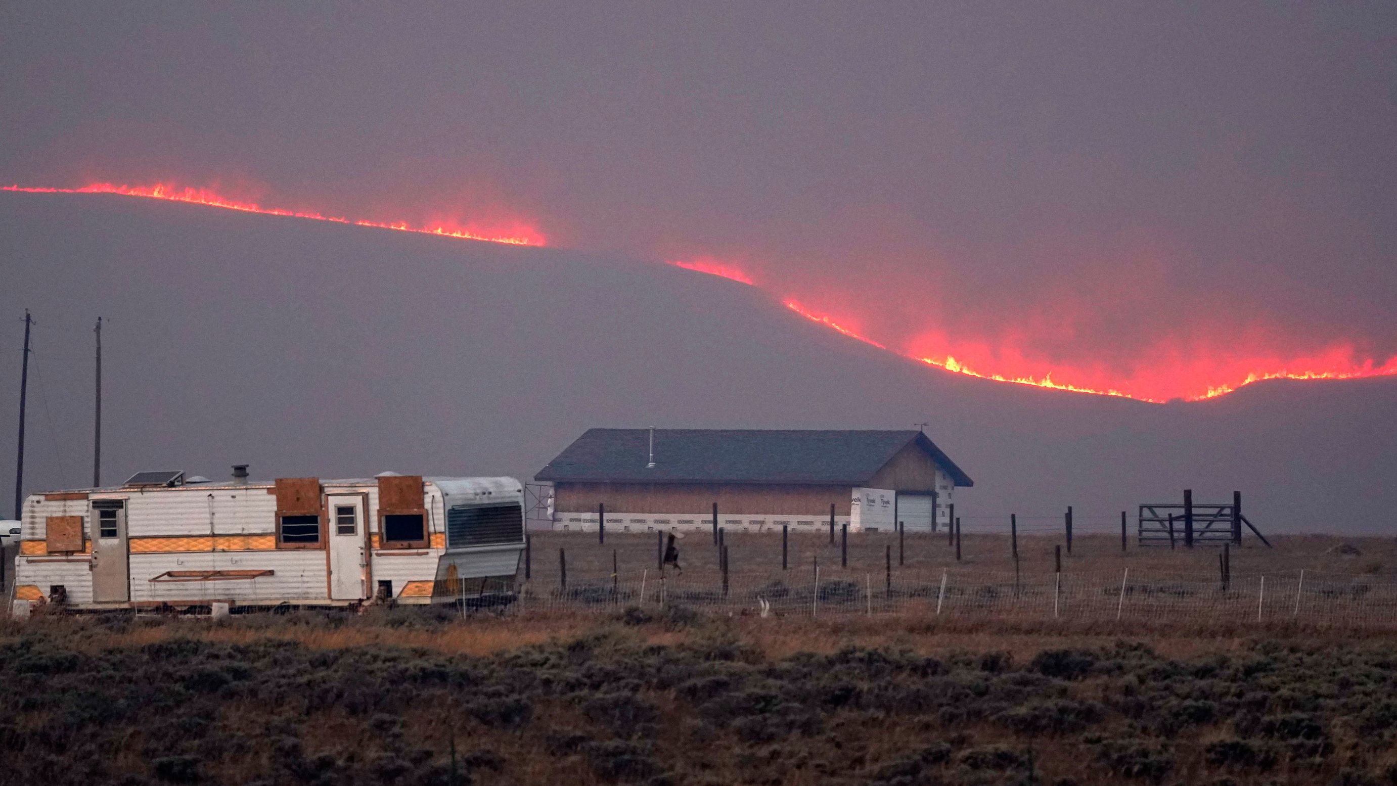 Flames rise from mountain ridges near a farmstead as a wildfire burns near Granby, Colorado, on Thursday, October 22, 2020.