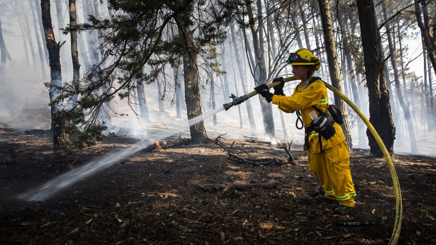 A firefighter waters a smoldering fire during the Diamond Fire in South San Francisco, California, U.S., on Friday, Oct. 16, 2020. 