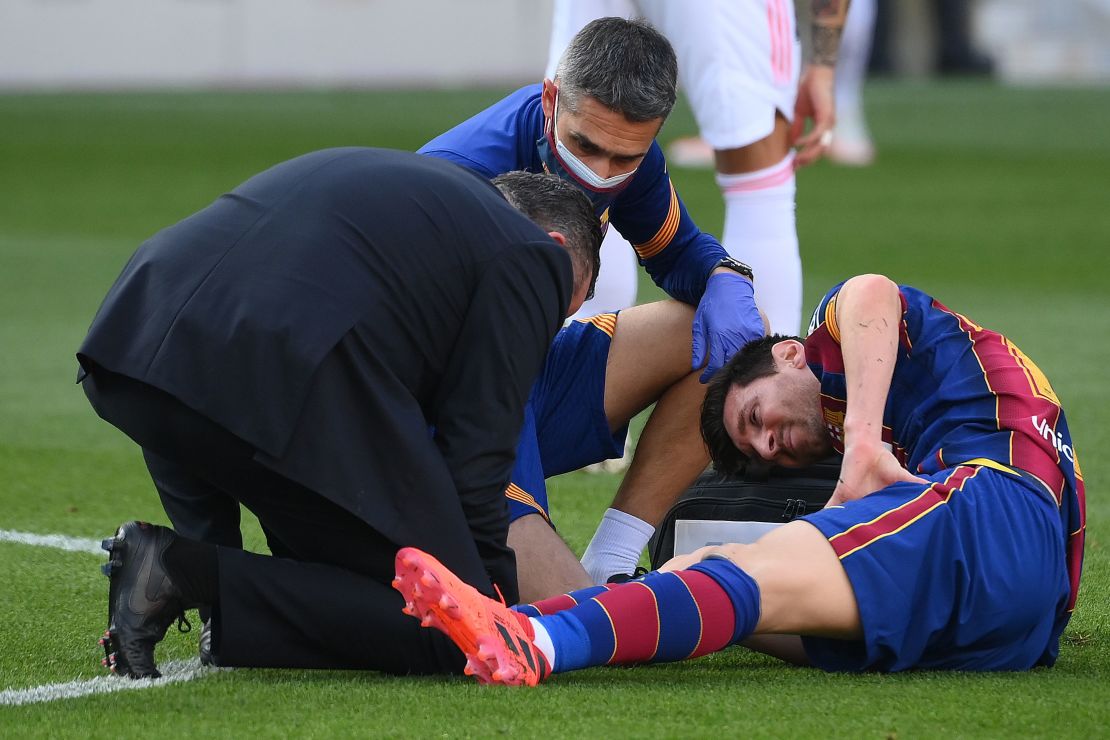 Messi receives medical attention after being tackled during the game against Real Madrid.