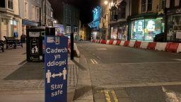 A social distancing sign is seen in an empty street during the first evening of the welsh lockdown, in Tenby, Wales on October 23