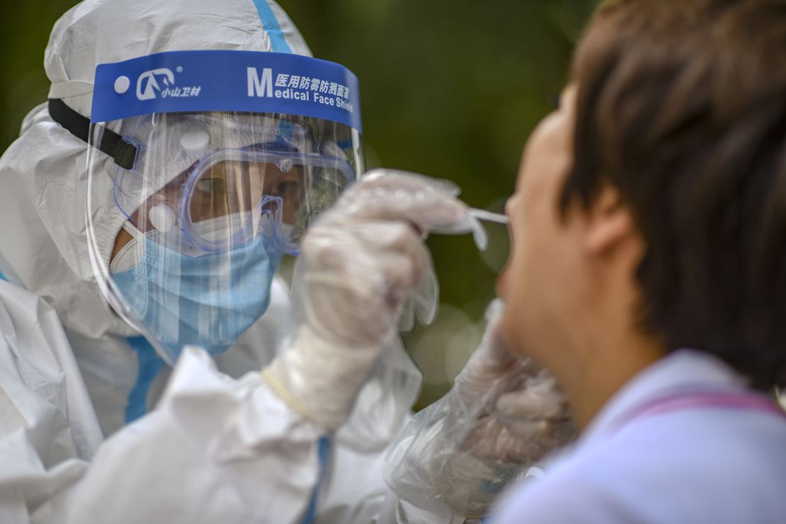 A medical worker collects a swab sample from a resident in Urumqi, Xinjiang during a citywide testing drive in July.