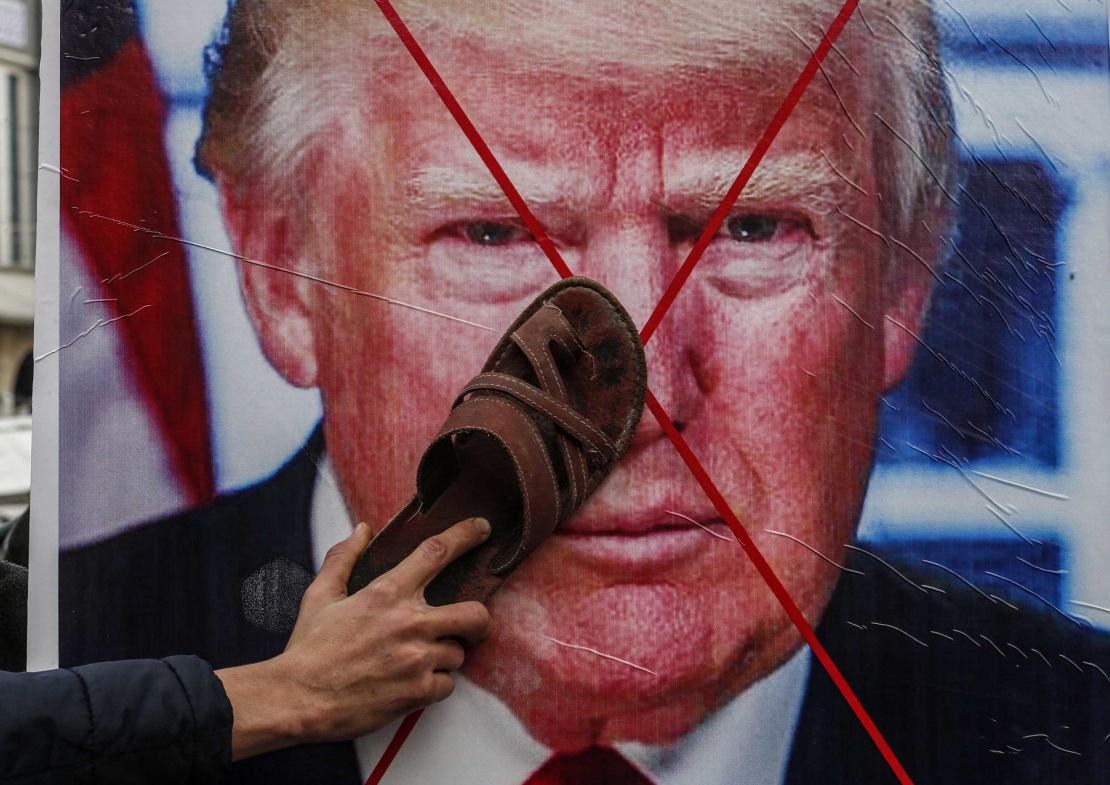 A Palestinian protester holds his sandal against a poster depicting US President Donald Trump during a demonstration against Trump's Middle East peace proposal in Khan Yunis, in the southern Gaza Strip, on February 3, 2020. 