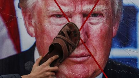 A Palestinian protester holds his sandal against a poster depicting US President Donald Trump during a demonstration against Trump's Middle East peace proposal in Khan Yunis, in the southern Gaza Strip, on February 3, 2020. 