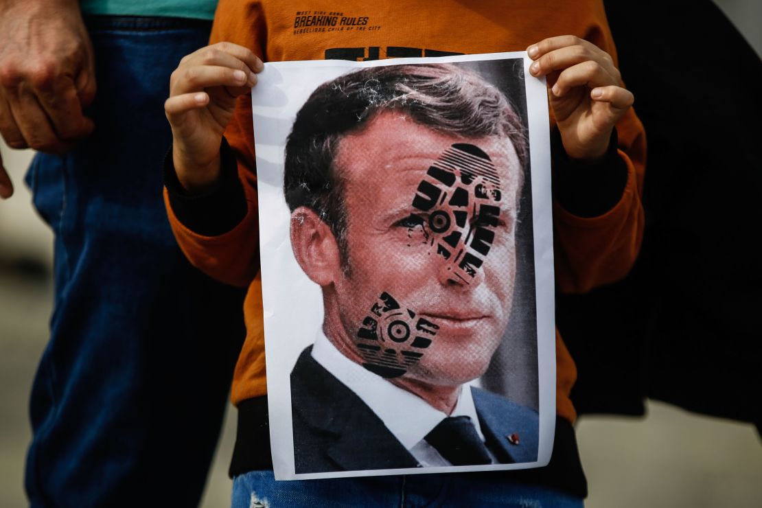 A child holds a photograph of Emmanuel Macron, stamped with a shoe mark, during a protest against France in Istanbul on October 25