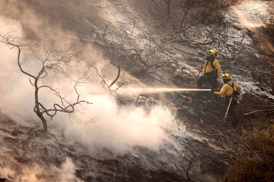 A firefighter uses a hose as the Silverado Fire approaches near Irvine, California.