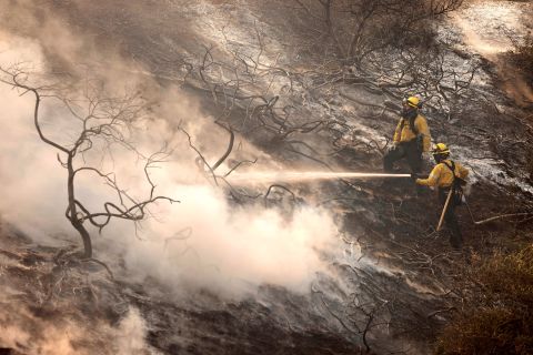 A firefighter uses a hose as the Silverado Fire approaches near Irvine, California.