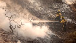 A firefighter uses a hose as the Silverado Fire approaches, near Irvine, California, on October 26, 2020. 