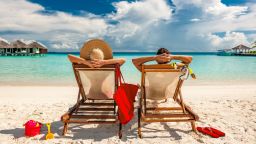underscored couple in folding chairs on beach vacation