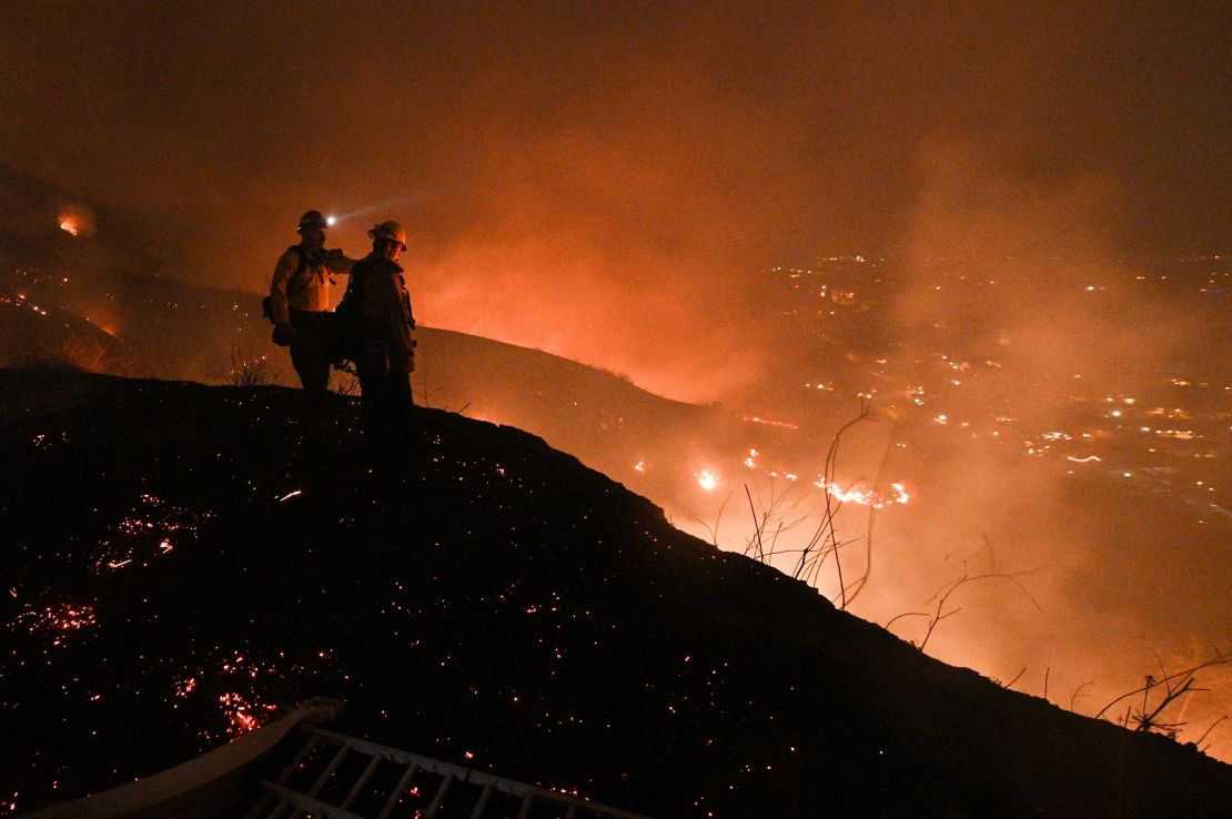 Firefighters look out over a burning hillside as they fight the Blue Ridge Fire in Yorba Linda, California, October 26, 2020.