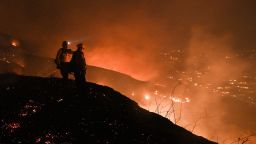Firefighters look out over a burning hillside as they fight the Blue Ridge Fire in Yorba Linda, California, October 26, 2020. - Some 60,000 people fled their homes near Los Angeles on October 26 as a fast-spreading wildfire raged across more than 7,200 acres (3,000 hectares), blocking key roadways and critically injuring two firefighters.