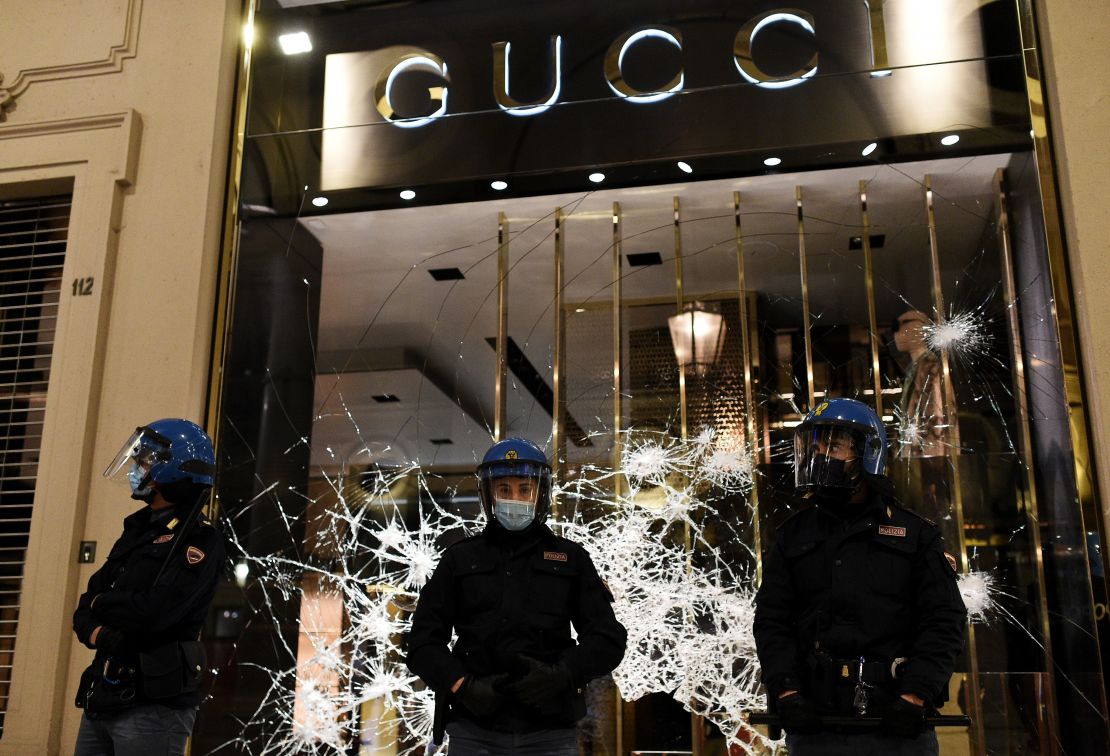 Italian police guard a shattered Gucci store window in Turin on Monday.