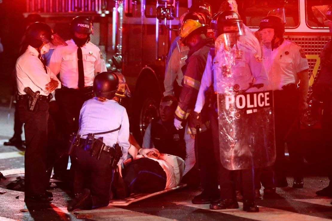 A police officer lies on the ground before being loaded into an ambulance on 52nd Street early on October 27.