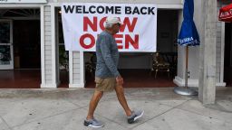 A man walks past a sign reading "Welcome Back, Now Open" on Fort Lauderdale Beach Boulevard in Fort Lauderdale, Florida on May 18, 2020. - South Florida begins a gradual reopening of its economy on May 18,2020 with the start of activities of some restaurants and businesses in Miami and Fort Lauderdale, but the beaches will still be closed until further notice.The opening "phase 1" in this region also does not include hotels, bars, nightclubs, gyms, movie theatres or massage parlours. (Photo by Chandan Khanna/AFP/Getty Images)