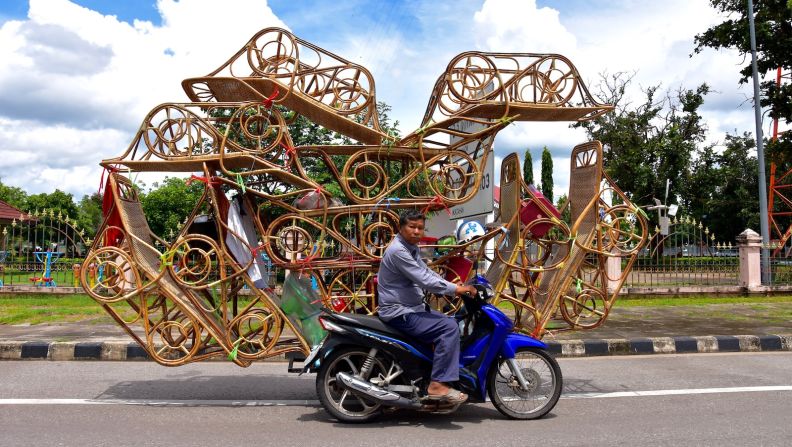 <strong>Heavy load:</strong> A man with some serious stacking skills transports lounge chairs in Nakhon Phanom province.