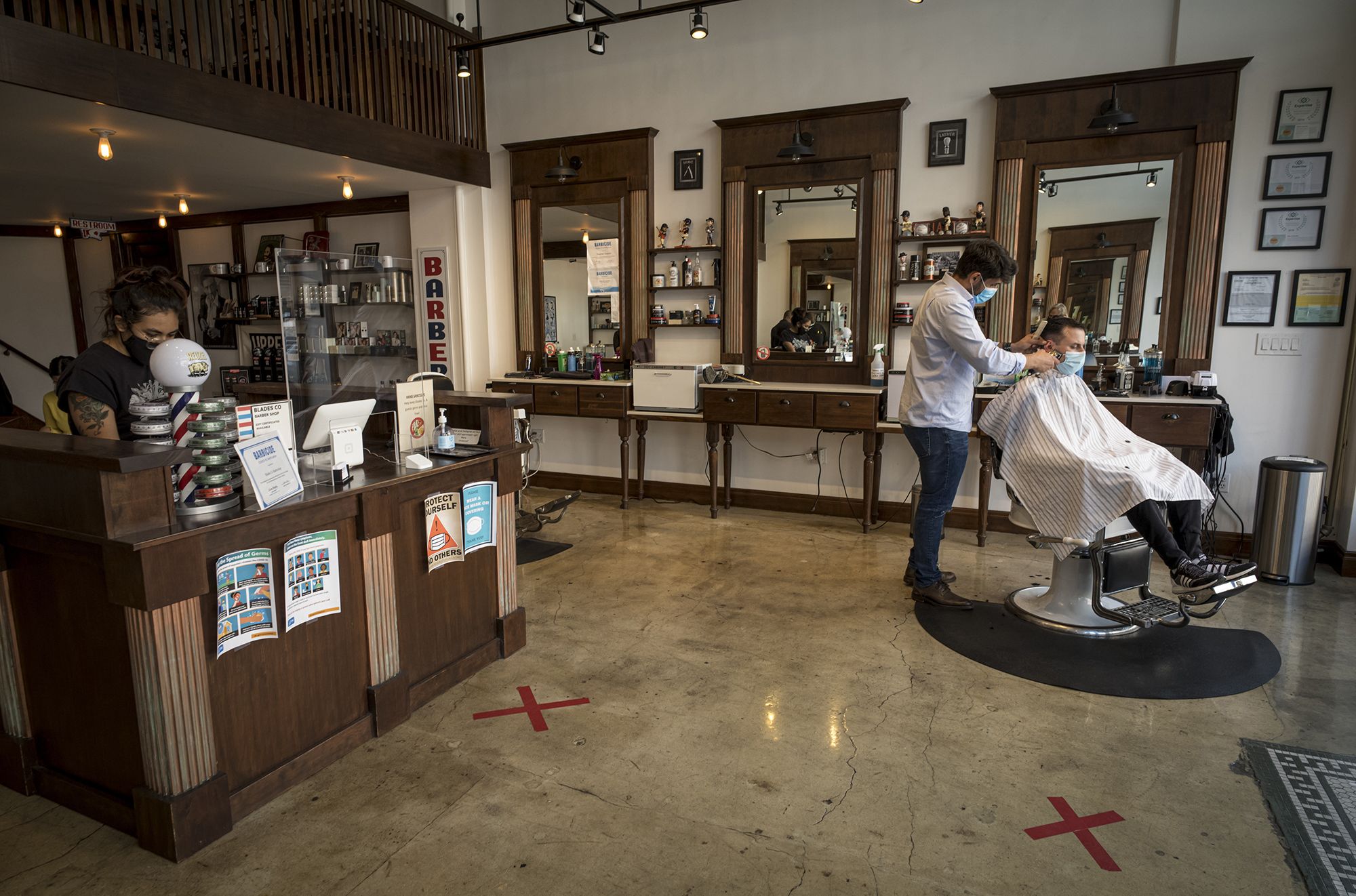A customer gets a haircut from a stylist wearing a protective mask at a barber shop in San Francisco, California, U.S., on Tuesday, Sept. 15, 2020. Thousands of San Francisco businesses were allowed to reopen Monday following a nearly six-month shuttering, according to the San Francisco Chronicle. Photographer: David Paul Morris/Bloomberg via Getty Images