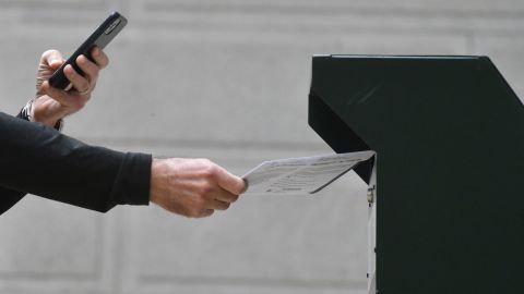 A man photographs himself depositing his ballot in an official ballot drop box while a long line of voters queue outside of Philadelphia City Hall at the satellite polling station on October 27, 2020 in Philadelphia, Pennsylvania. 