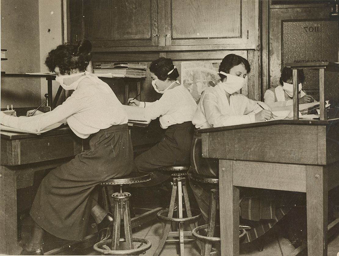 Female clerks in New York work with masks tied around their faces on October 16, 1918.