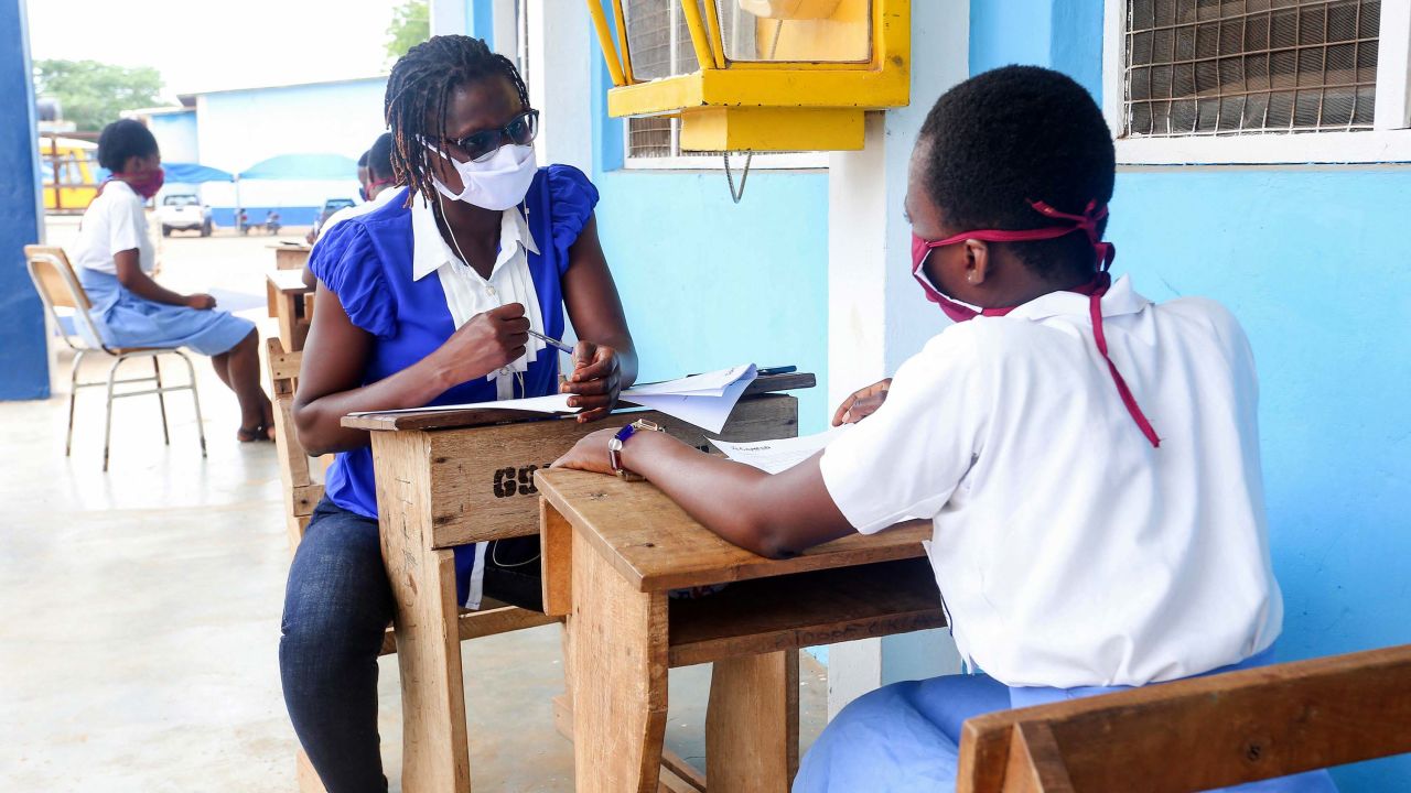 A teacher and student meet outside, wearing masks and maintaining social distancing.