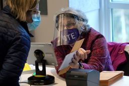 A well-protected poll worker in Newton, Mass., cuts down on the risk of voting. Do your part by wearing a mask and social distancing. 