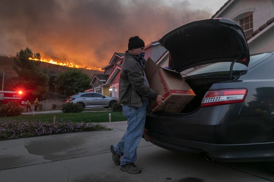A man evacuates his home as flames from the Blue Ridge Fire approach in Chino Hills, California, on Tuesday, October 27, 2020.