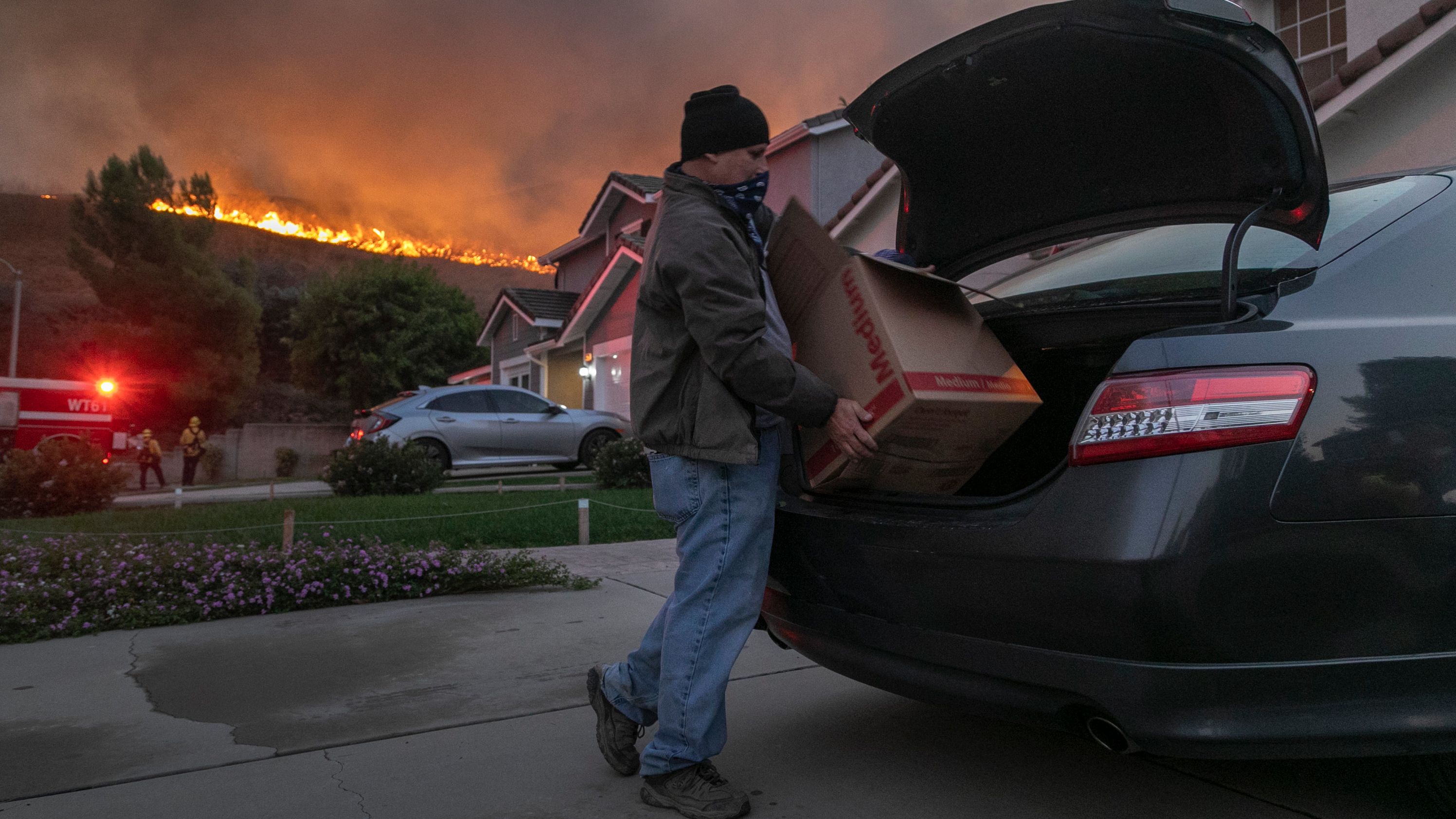 A man evacuates his home as flames from the Blue Ridge Fire approach in Chino Hills, California, on Tuesday, October 27, 2020.