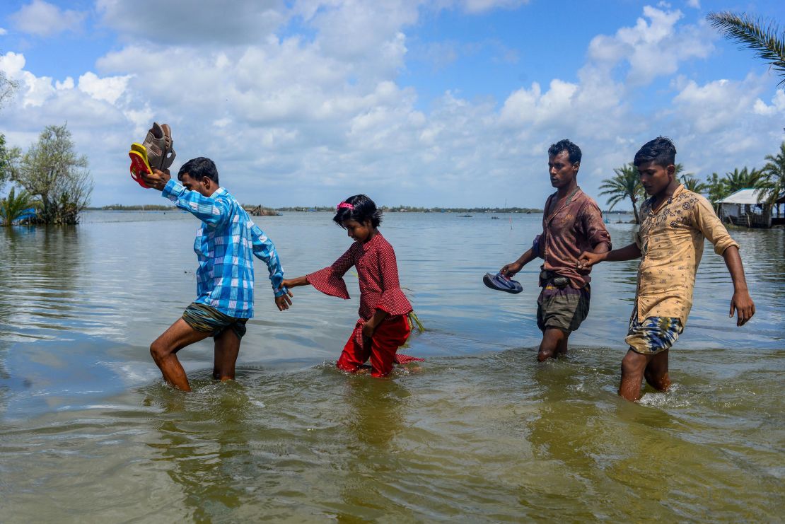 People cross the broken flooded road after the landfall of Cyclone Amphan in Bangladesh. 