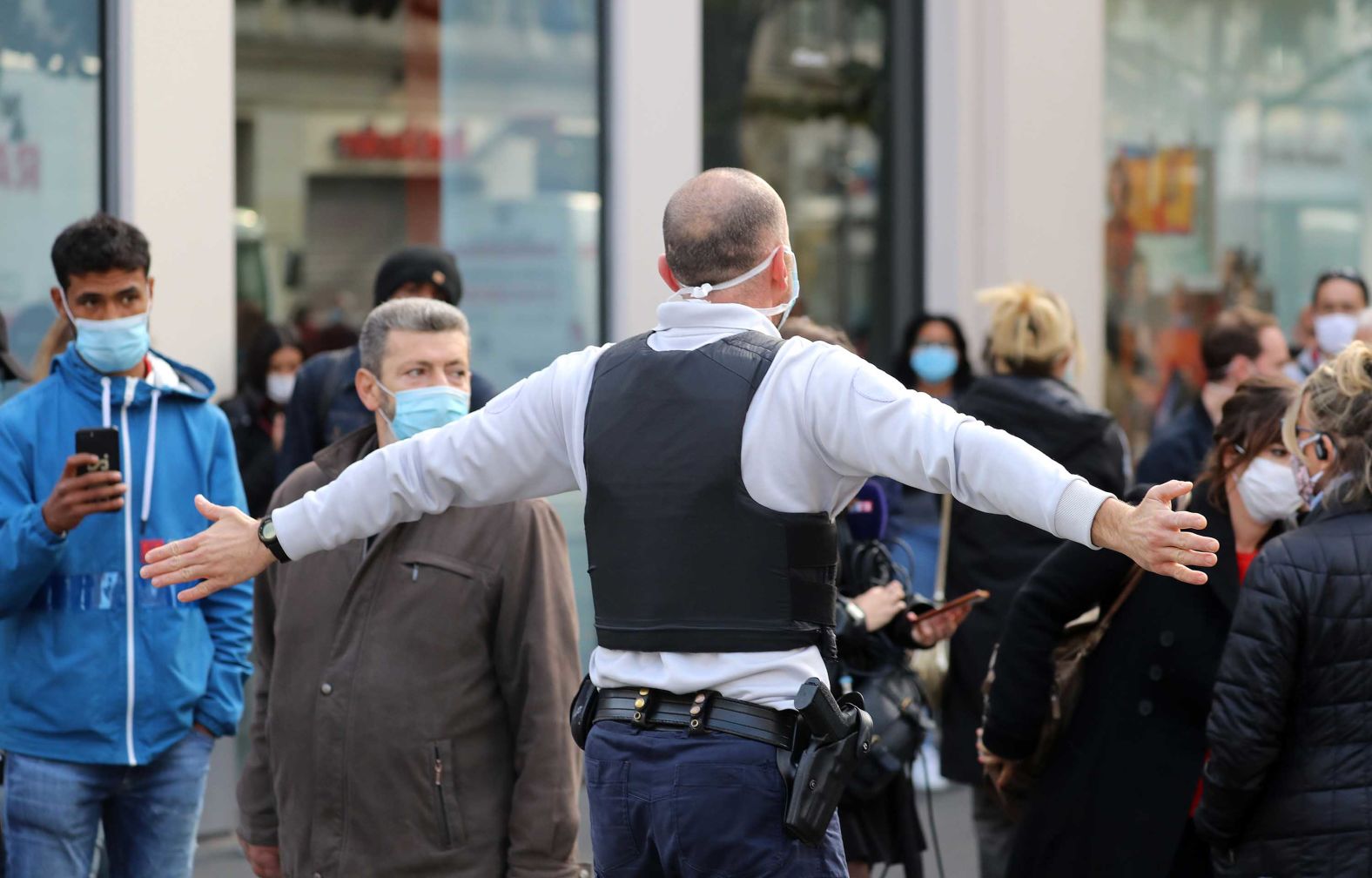 A police officer pushes bystanders back from the area.