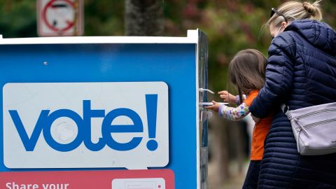 Finley Vong, 3, helps her mother, Tiffany Anderson, drop a ballot into a drop box Wednesday in Seattle.