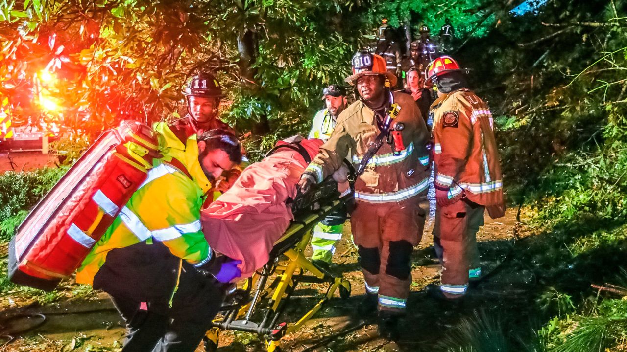 Atlanta firefighters transport a man they freed who was trapped in his third-floor bedroom after a tree came down on a home Thursday. 